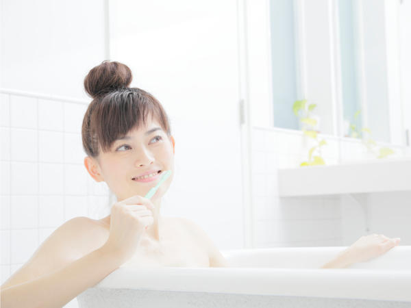 お風呂で歯を磨く女性の写真